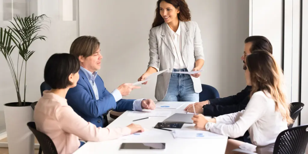 Professionisti sorridenti riuniti attorno a un tavolo modulare in una luminosa sala riunioni a Torino all'interno del nostro Coworking.